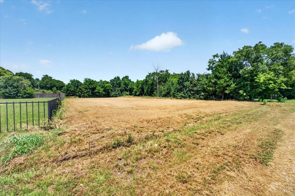 1306 Ranch Road Grand Prairie, TX 75052 - Photo 4 of 13 Expansive cleared lot with mature perimeter trees and a black metal fence