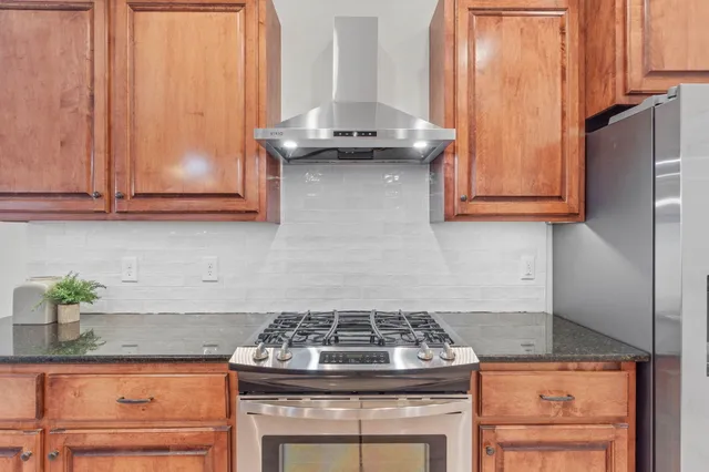 a kitchen with stainless steel appliances granite countertop a sink a stove and a wooden floors