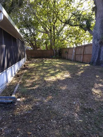 a view of a backyard with large trees and wooden fence