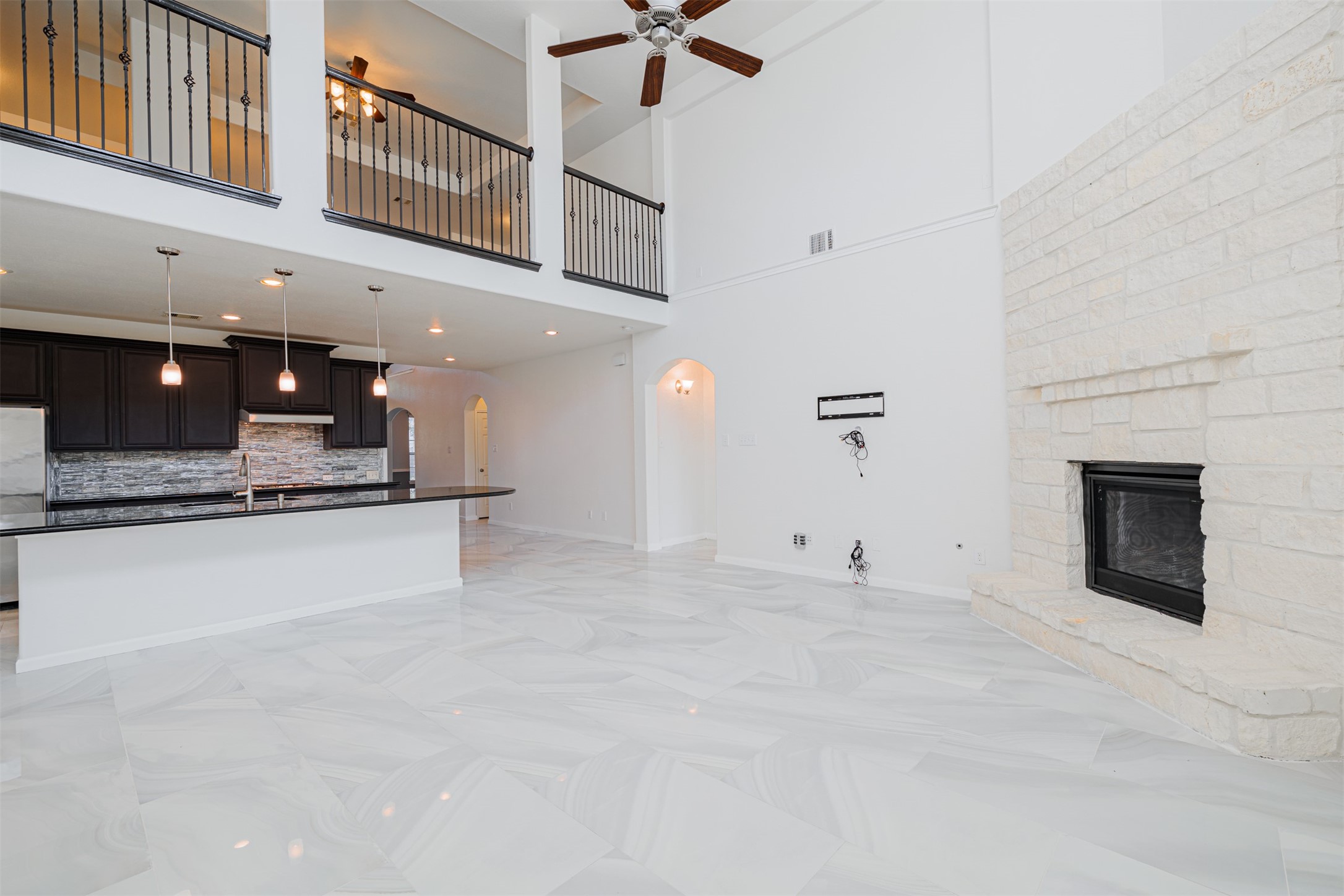 7814 Pacific Spring Lane Richmond, TX 77407 - Photo 14 of 32 a large white kitchen with a fireplace and a ceiling fan