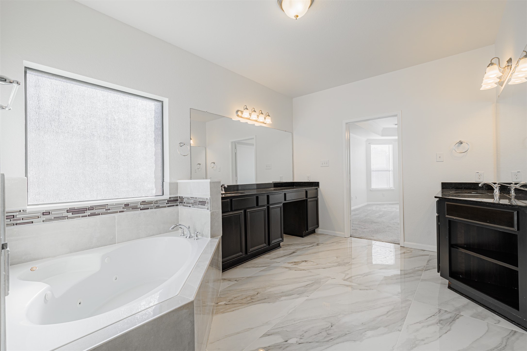 7814 Pacific Spring Lane Richmond, TX 77407 - Photo 20 of 32 a spacious bathroom with a tub sink and mirror