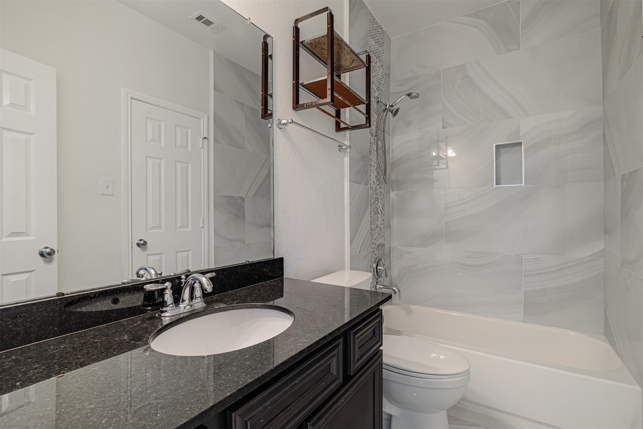 7814 Pacific Spring Lane Richmond, TX 77407 - Photo 9 of 32 a bathroom with a granite countertop sink toilet a mirror a bathtub and shower