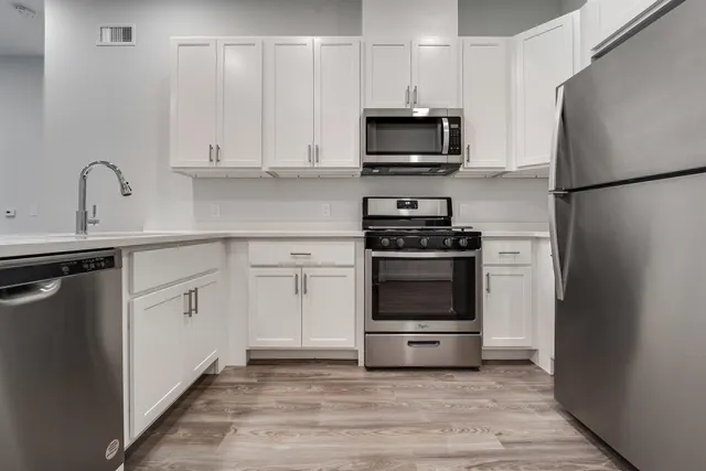 a kitchen with white cabinets and stainless steel appliances