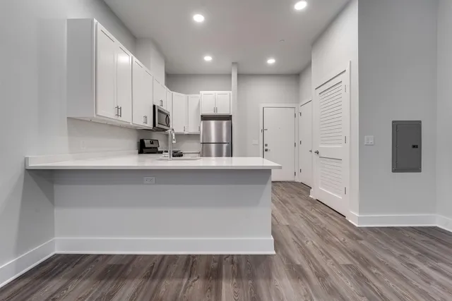 a large kitchen with stainless steel appliances a large white counter top a wooden floors and a fireplace