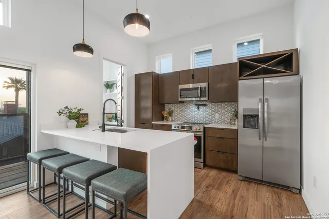 a kitchen with stainless steel appliances granite countertop a refrigerator a stove a sink and chairs