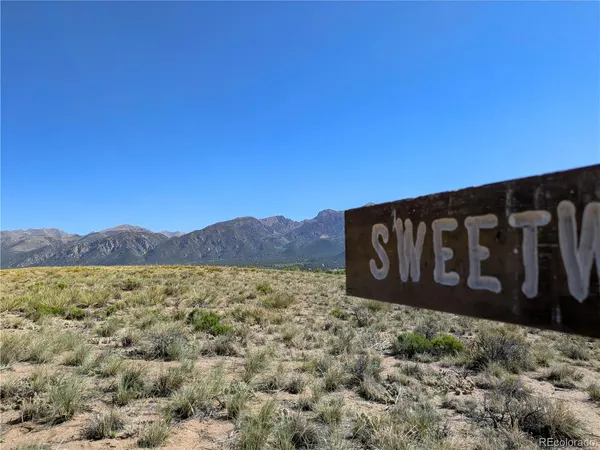 a view of a wooden sign under a large mountain