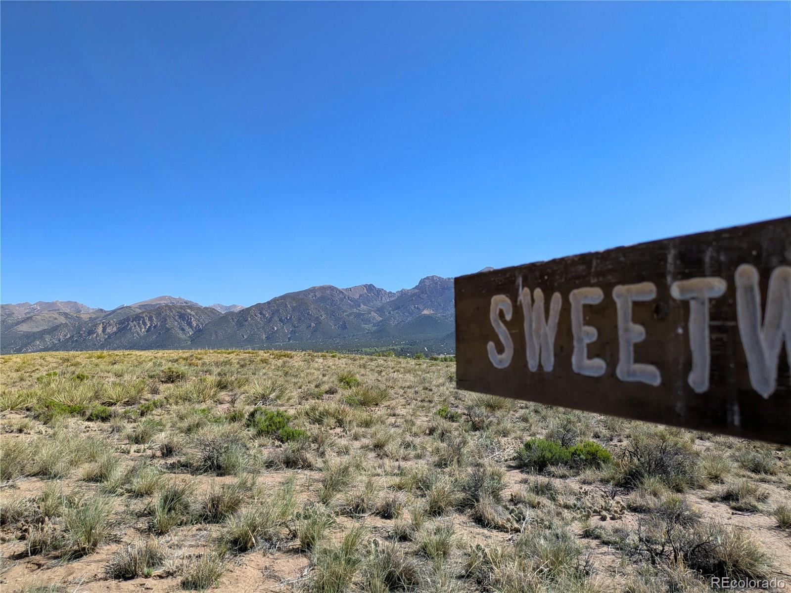a view of a wooden sign under a large mountain