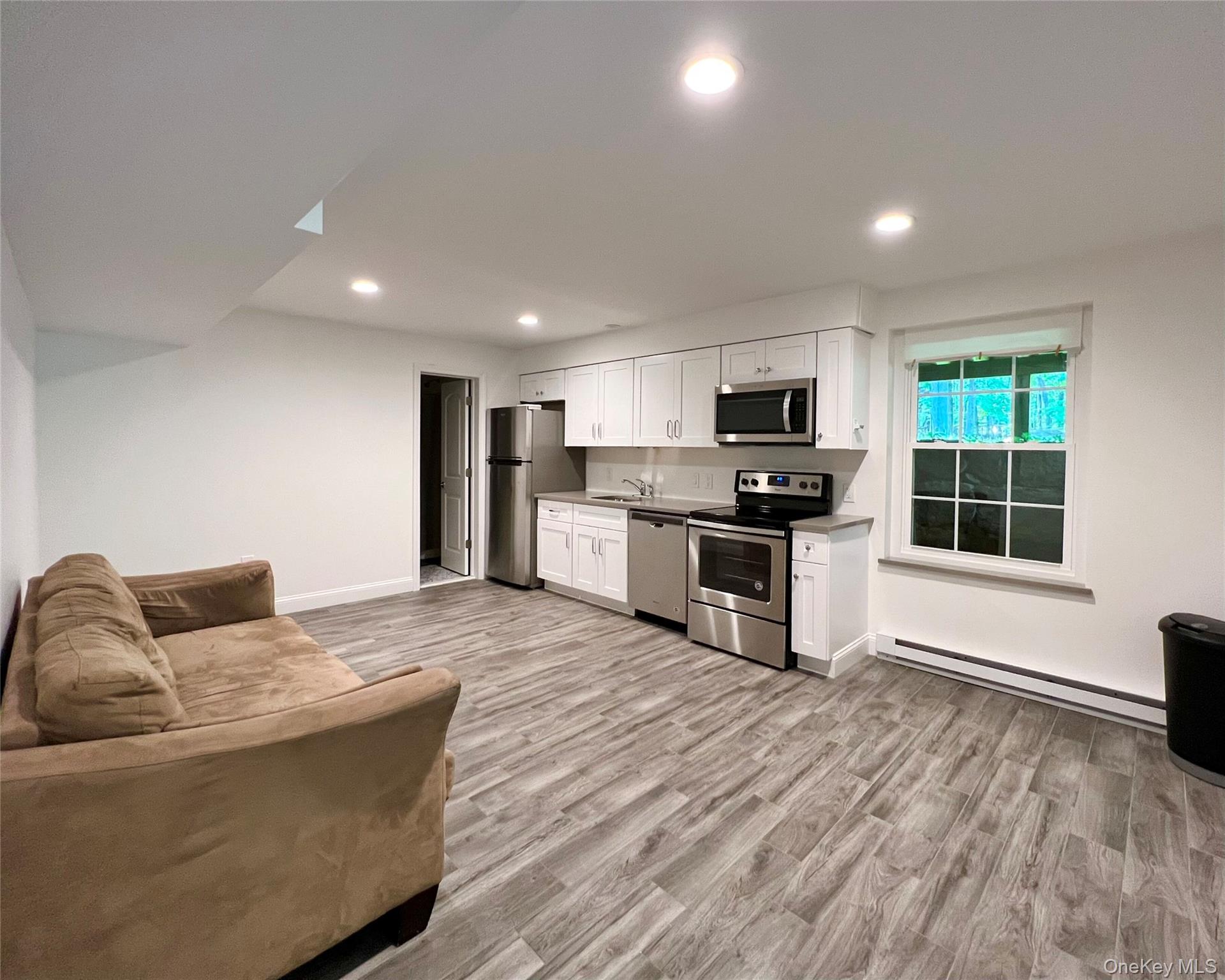 a living room with stainless steel appliances furniture microwave and wooden floor