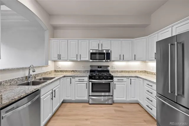 a kitchen with white cabinets and stainless steel appliances