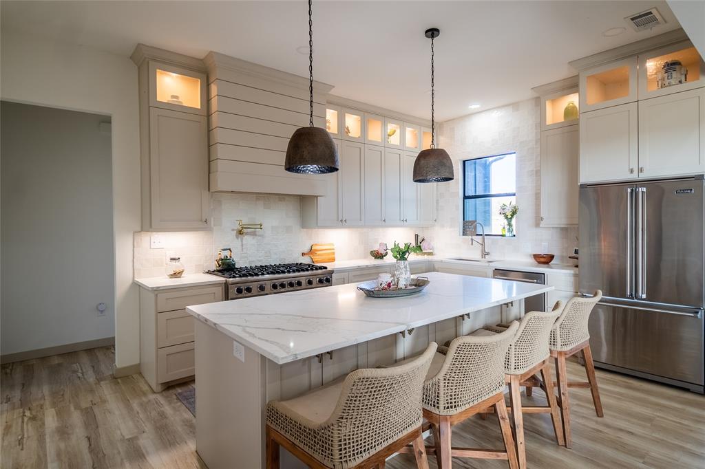375 Wolf Front Road Van Alstyne, TX 75495 - Photo 9 of 40 a kitchen with stainless steel appliances granite countertop a stove a refrigerator a sink a dining table and chairs with wooden floor