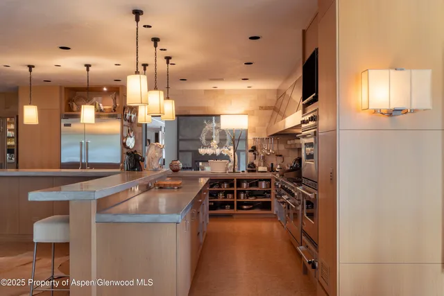 a dining hall with stainless steel appliances kitchen island granite countertop a table chairs in it and a counter top