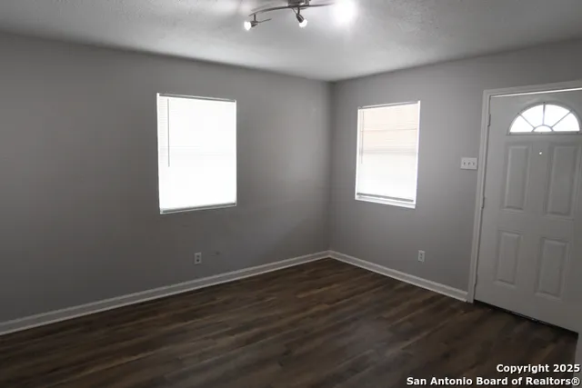 an empty room with wooden floor and windows