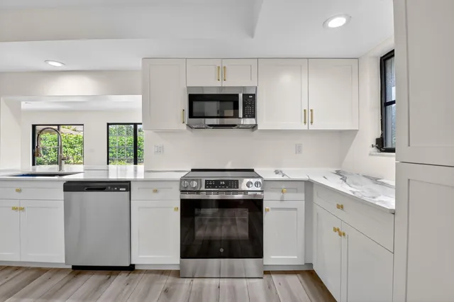 a kitchen with white cabinets stainless steel appliances and sink