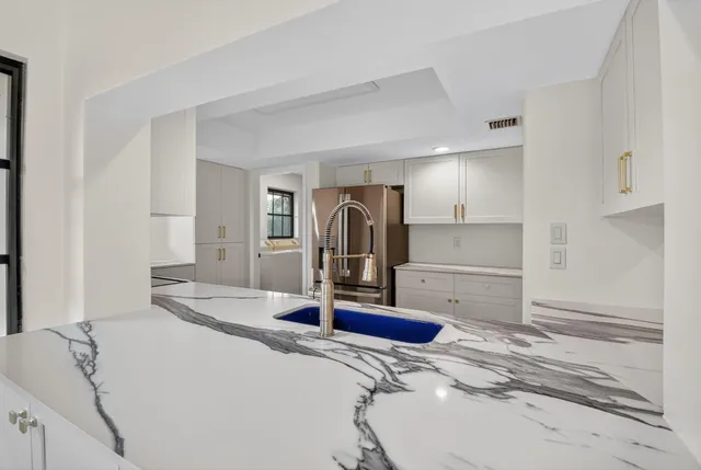 a large white kitchen with sink and cabinets