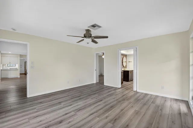 a view of an empty room with wooden floor and a window