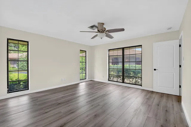 a view of an empty room with wooden floor and a window
