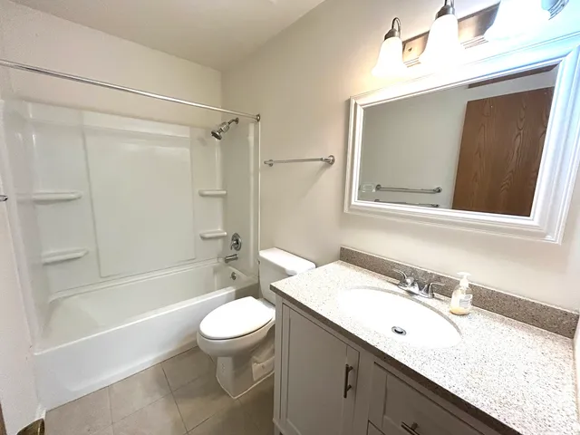 a bathroom with a granite countertop sink a toilet and shower