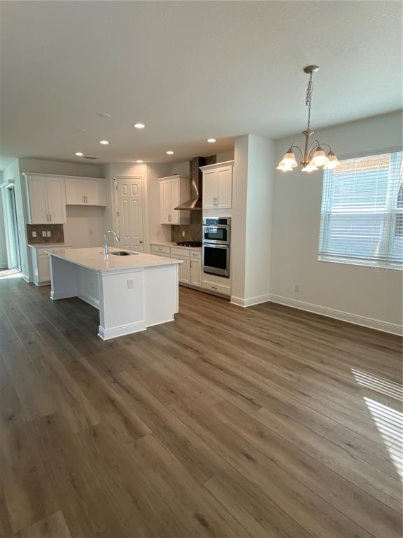 435 Lemongrass Road Minneola, FL 34715 - Photo 6 of 21 a view of a kitchen with kitchen island a sink wooden floor and a living room view