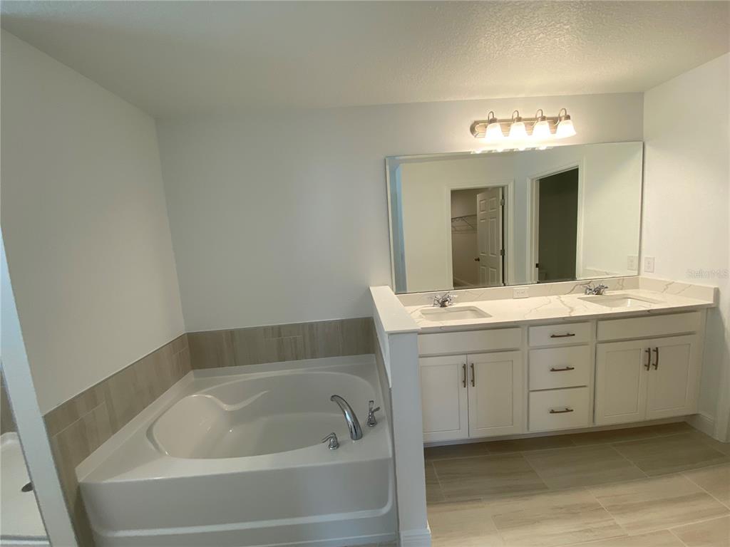 435 Lemongrass Road Minneola, FL 34715 - Photo 10 of 21 a bathroom with a tub a double vanity sink and a mirror