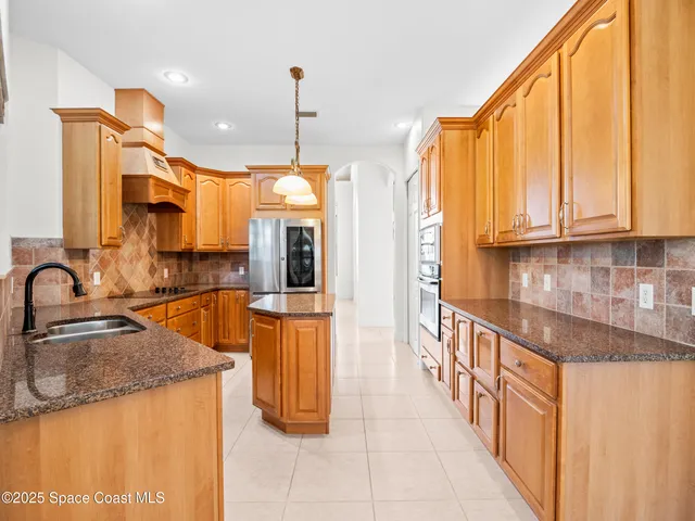 a kitchen with stainless steel appliances granite countertop a sink a stove and a wooden cabinets