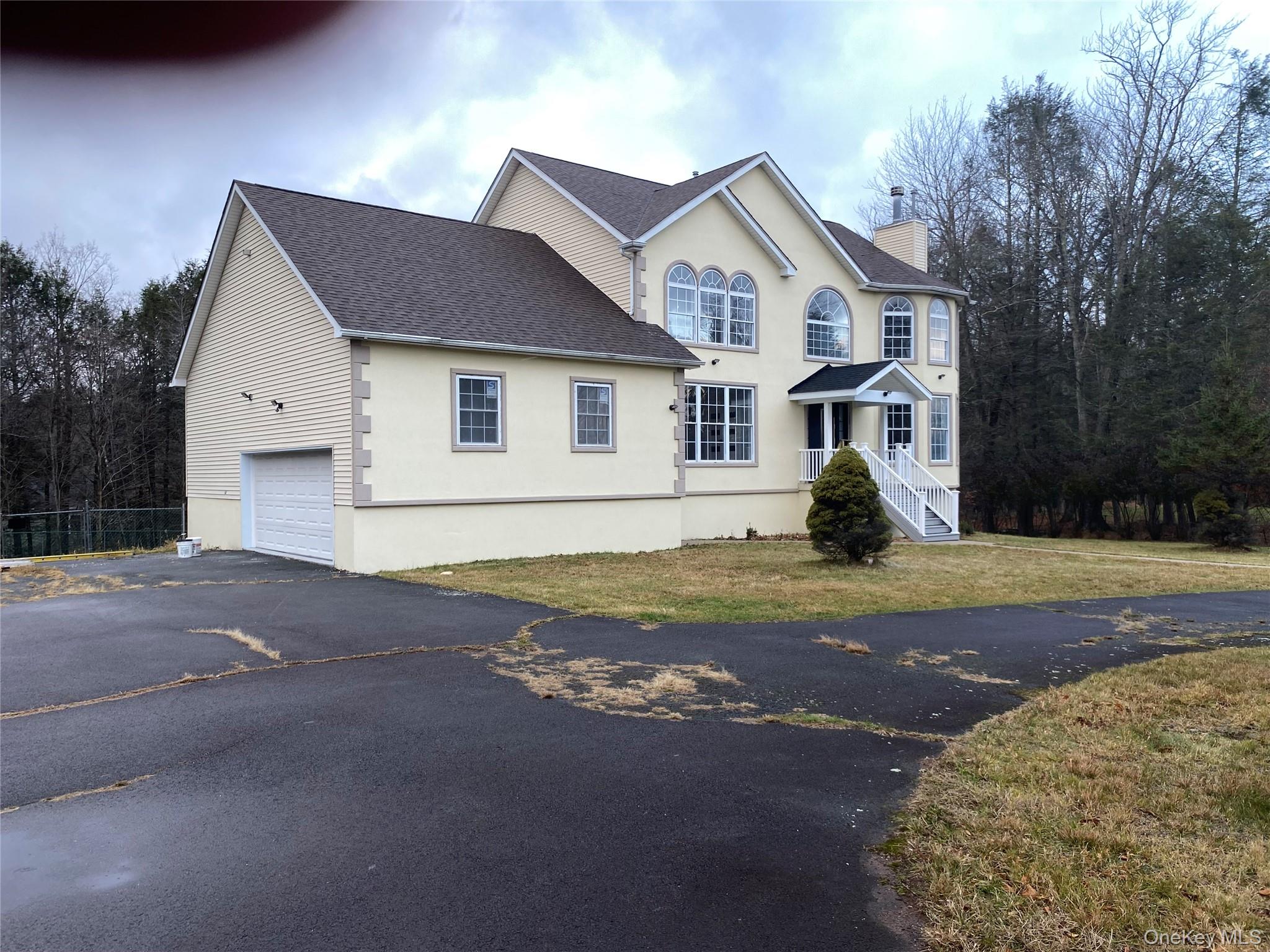 44 Roslyn Ridge Road Mongaup Valley, NY 12762 - Photo 2 of 24 View of front of house featuring asphalt driveway, stucco siding, an attached garage, a shingled roof, and a chimney