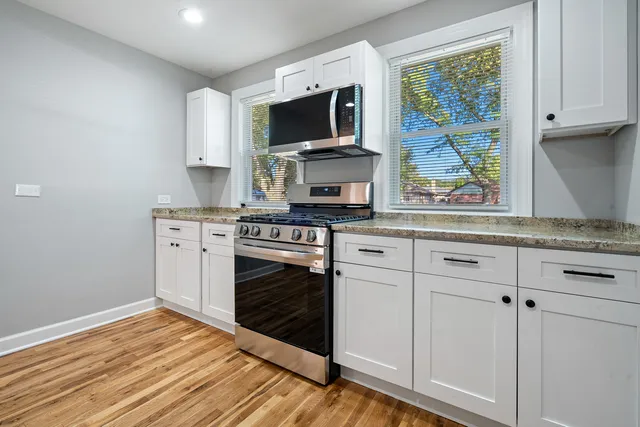 a kitchen with stainless steel appliances white cabinets and a stove top oven