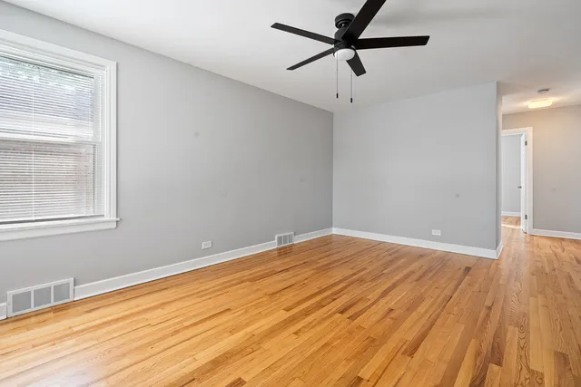 a view of empty room with wooden floor and fan
