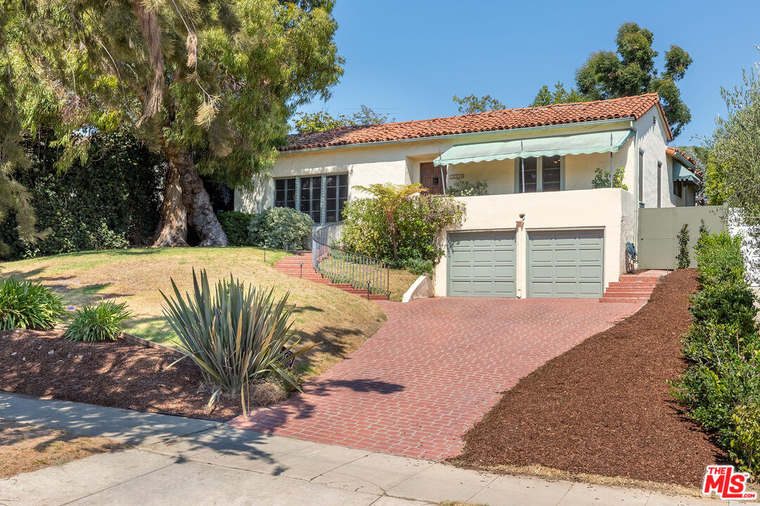 a front view of a house with a yard and potted plants