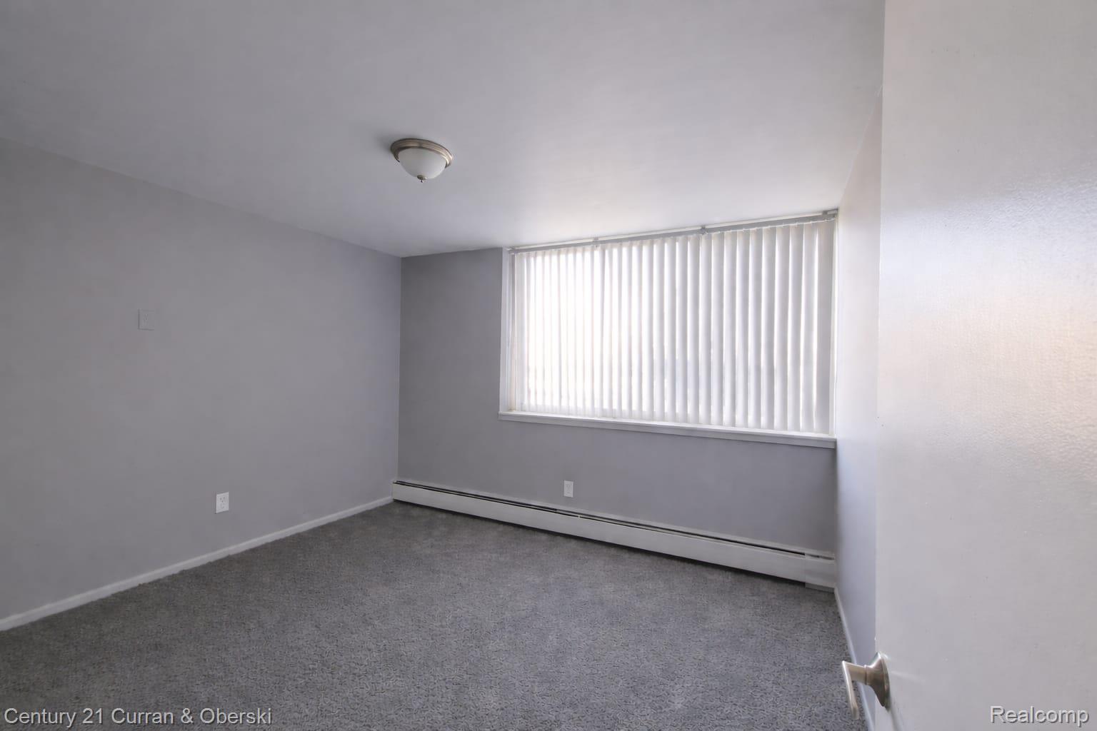 6035 Southfield Road, Unit 12 Detroit, MI 48228 - Photo 7 of 10 Empty room with a baseboard heating unit and carpet floors
