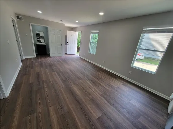 an empty room with wooden floor and windows