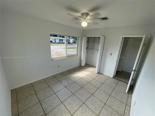 an empty room with windows and fan