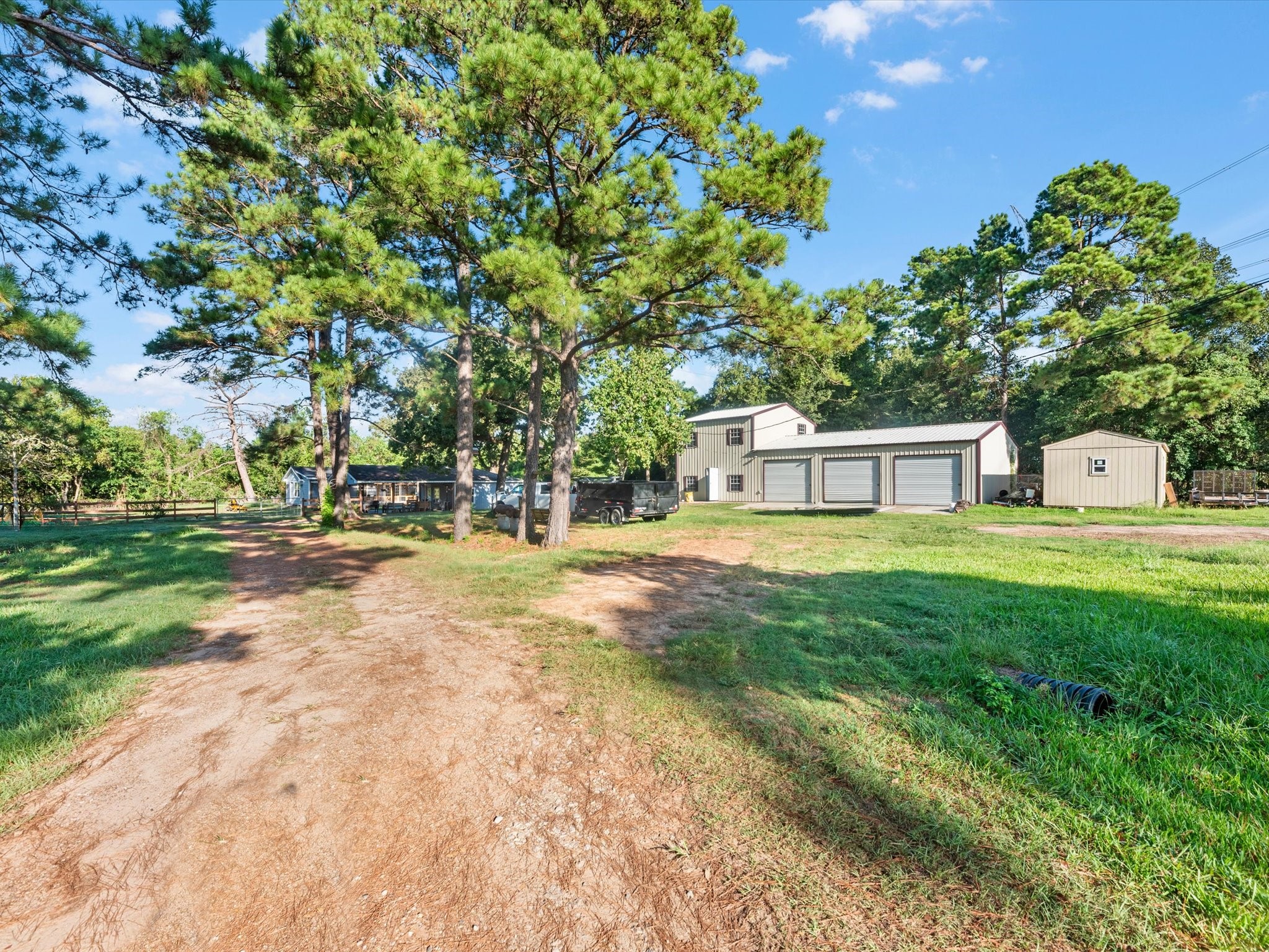 32403 Dobbin-Huffsmith Road Magnolia, TX 77354 - Photo 3 of 31 Driveway leading to Structures 1 and 2. Structure 1 features a spacious 3-car garage with a 1-bedroom, 1-bath loft above. Structure 2 offers approximately 200 sq ft with a 1-bedroom layout.