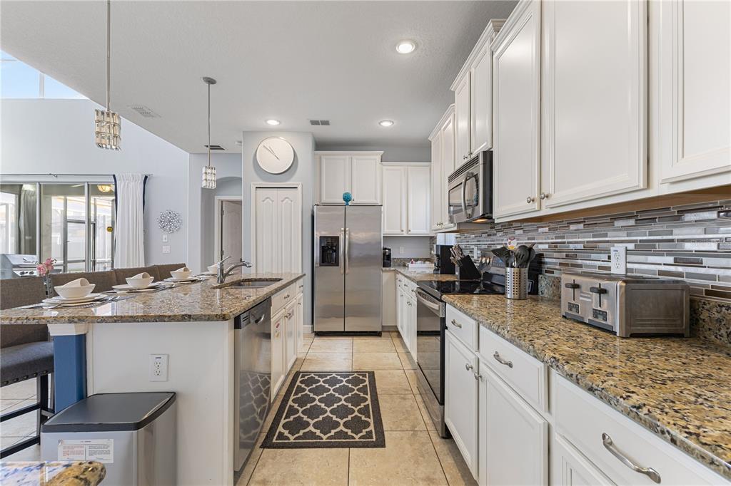9006 Majesty Palm Road Kissimmee, FL 34747 - Photo 19 of 56 a kitchen with stainless steel appliances granite countertop a stove a sink and a refrigerator