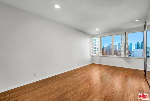 a view of an empty room with wooden floor and window