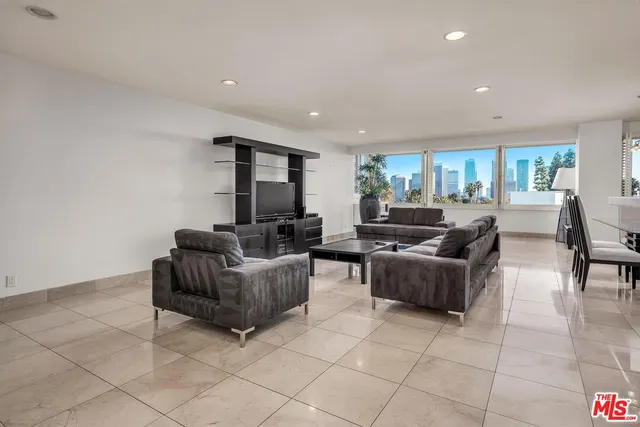 a living room with couches and a dining table with kitchen view