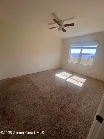 an empty room with a ceiling fan and window