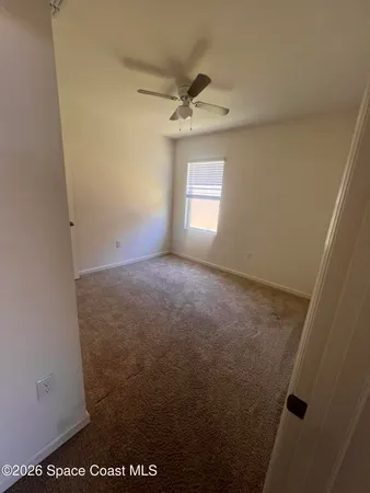 an empty room with a window and a ceiling fan