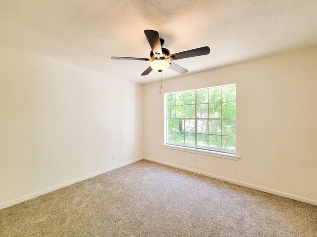 an empty room with a window and a fan