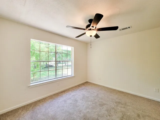 an empty room with a window and a fan