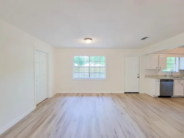 an empty room with wooden floor and windows