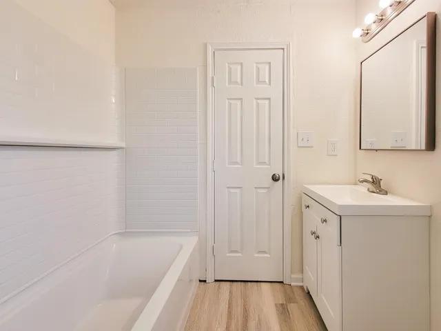 a bathroom with a tub sink and mirror
