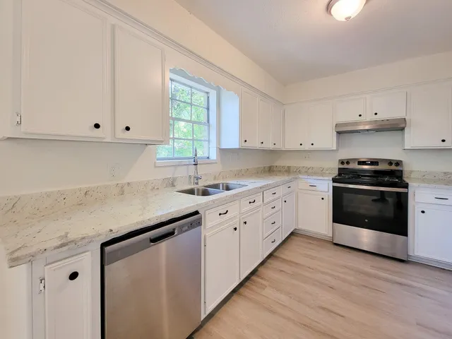 a kitchen with granite countertop white cabinets and white appliances