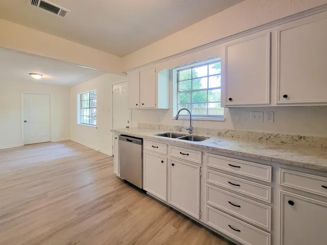 a kitchen with granite countertop white cabinets and a sink