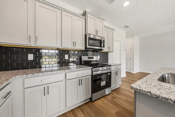 a kitchen with granite countertop white cabinets and stainless steel appliances