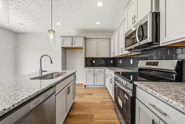 a kitchen with stainless steel appliances granite countertop a sink stove and cabinets