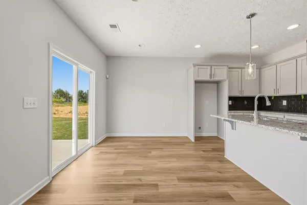 a view of kitchen with stainless steel appliances granite countertop a stove a refrigerator a sink and white cabinets with wooden floor