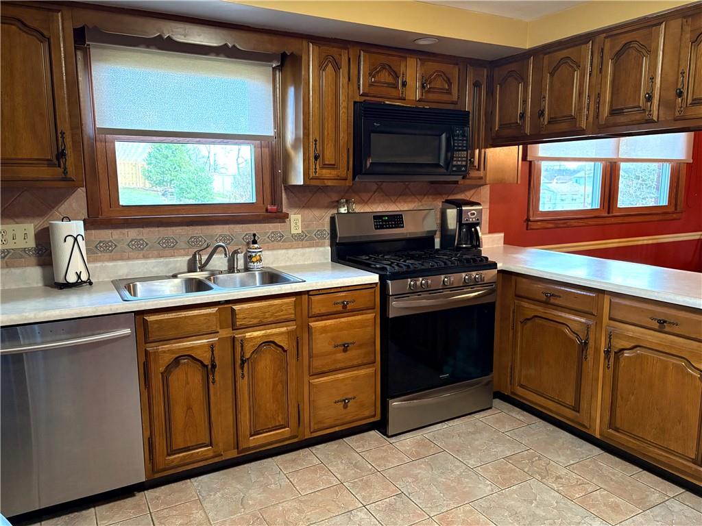 5719 Halchess Street Pittsburgh, PA 15207 - Photo 10 of 25 a kitchen with stainless steel appliances a stove sink microwave and cabinets