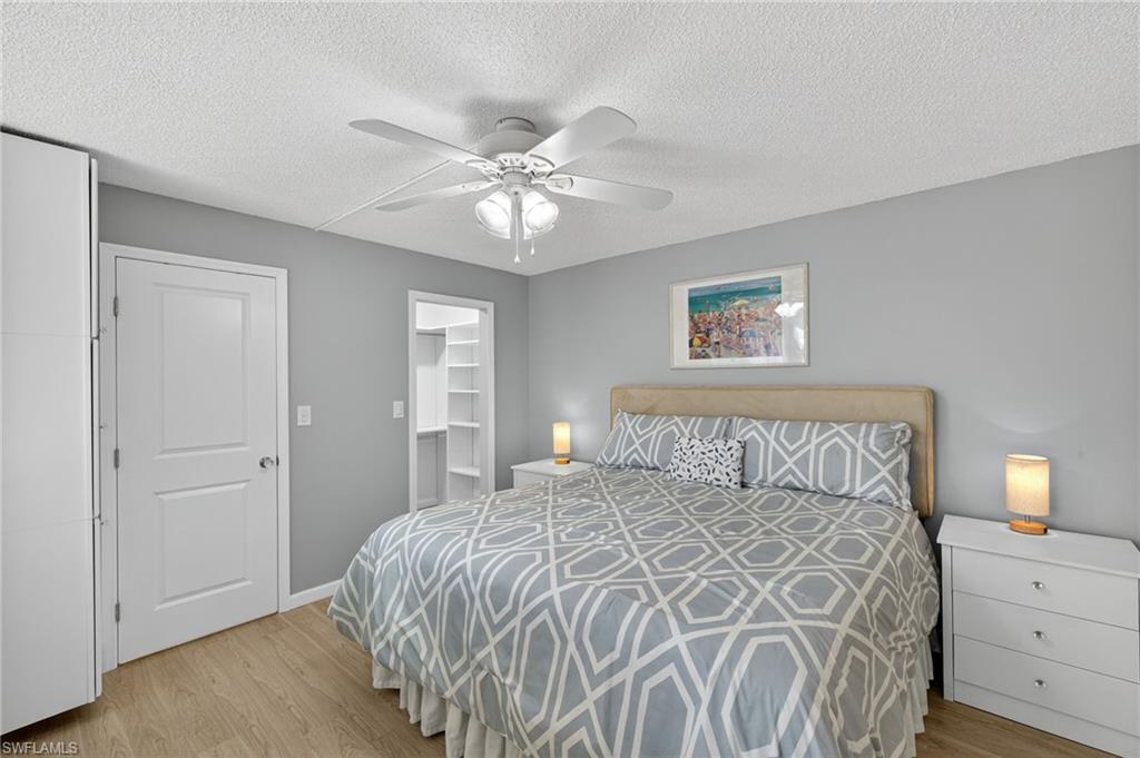 5900 Bonita Beach Road Southwest, Unit 1602 Bonita Springs, FL 34134 - Photo 11 of 26 Bedroom with light wood finished floors, a textured ceiling, a walk in closet, and ceiling fan