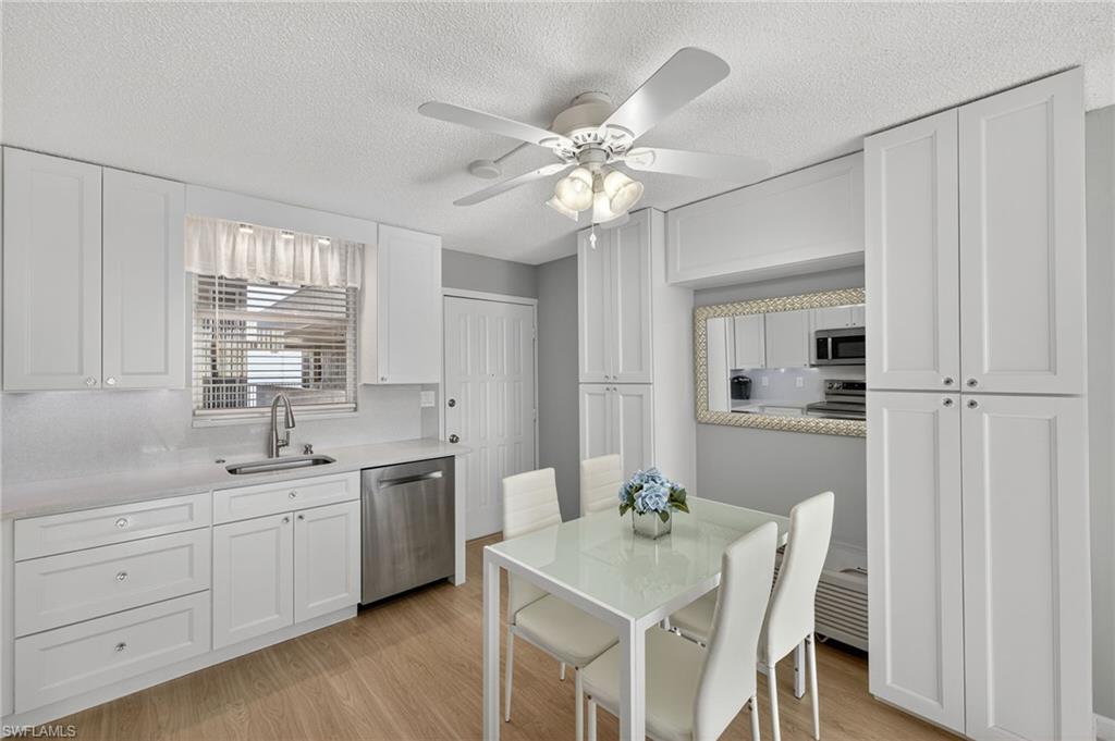 5900 Bonita Beach Road Southwest, Unit 1602 Bonita Springs, FL 34134 - Photo 8 of 26 Kitchen featuring white cabinets, light wood-type flooring, appliances with stainless steel finishes, ceiling fan, and a textured ceiling