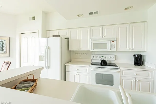 a kitchen with white cabinets and white appliances